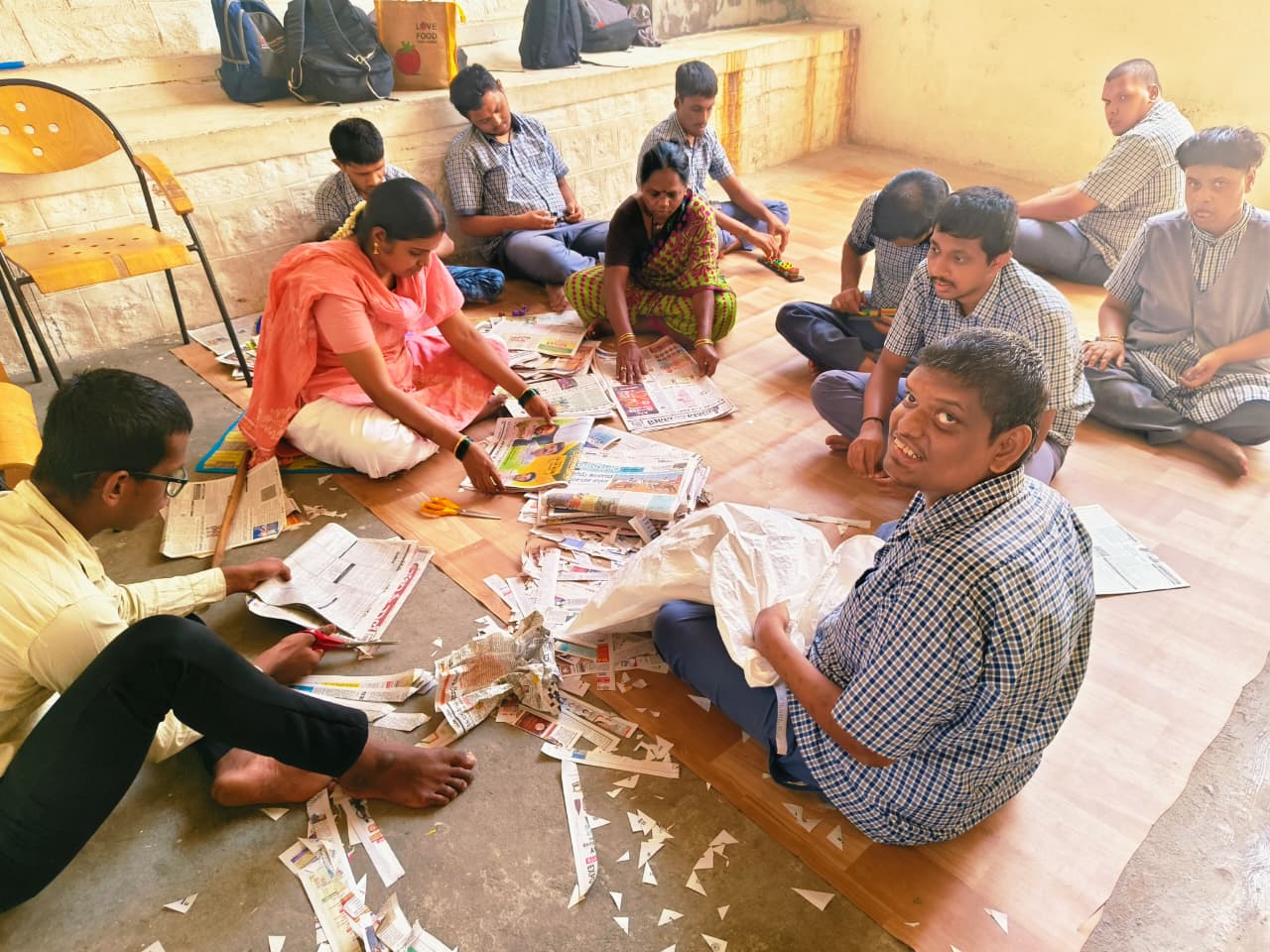 Students and staff working together with newspapers for craft and sorting activities